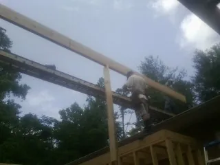 Carpenter setting a ridge beam over a new addition frame — Ice Dam Removal by Roofing Brothers in Wellsville