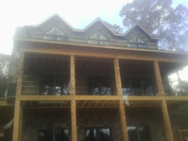 Dormers and porch framing on a large log home under construction — Roof Coating work by our crew in Wellsville