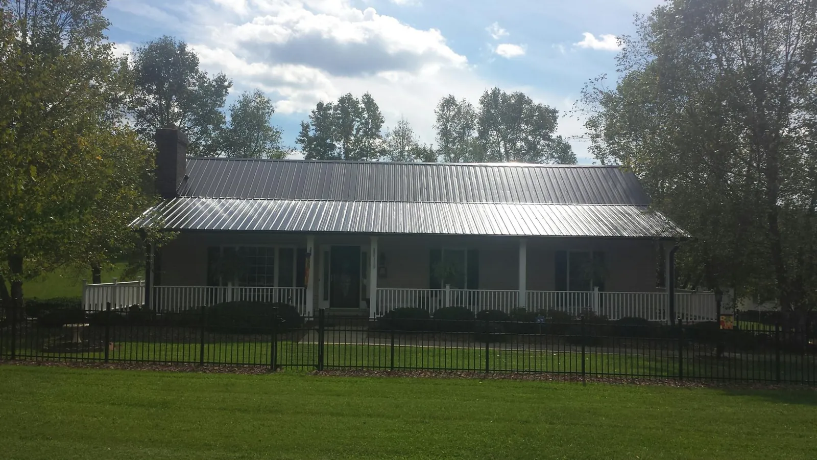 Gray metal roof on a brick ranch with a full width front porch — Gutter Guard Installation work by our crew in Wellsville